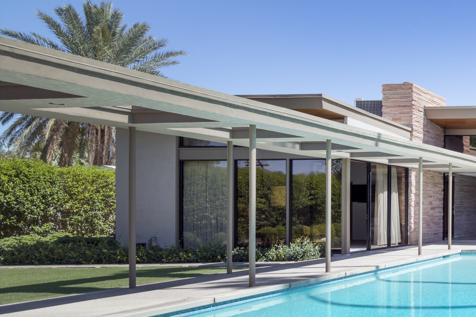 Inspiration photo: a long covered walkway beside floor-to-ceiling glass walls and a pool