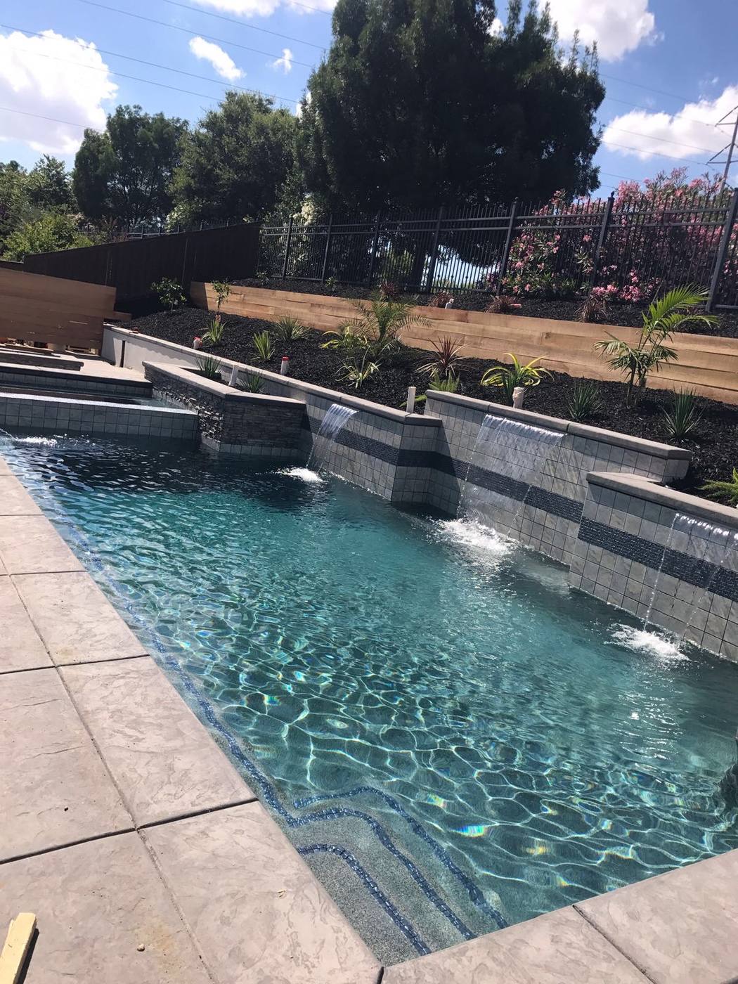 Rectangular pool with three sheer-descent water features falling from a tiled raised wall
